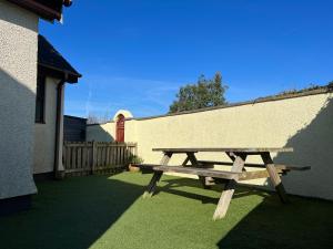 a wooden picnic table sitting next to a building at Detached 3 Bed Cottage Mountain Views- Pets Wifi in Beaumaris