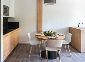 a kitchen and dining room with a wooden table and white chairs at Ambiez Residencehotel in Madonna di Campiglio