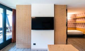 a room with a flat screen tv on a wall at Ambiez Residencehotel in Madonna di Campiglio