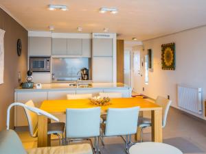 eine Küche mit einem Holztisch und weißen Stühlen in der Unterkunft Appartement 1 bedroom with parking at Darwin II 0901 on floor 9 in Middelkerke