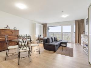 a living room with a couch and a table and chairs at Spacious studio with storage room in Blankenberge