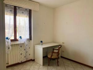 Habitación con escritorio, silla y ventana. en Aria di casa affittacamere, en Badesse
