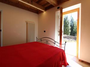 1 dormitorio con cama roja y puerta corredera de cristal en Pleasant holiday home in Lozzo di Cadore with garden, en Vigo di Cadore