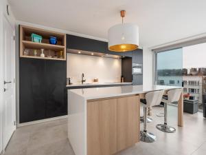 een keuken met een aanrecht en een bar met krukken bij Castelli - Secundo 302 - Appartment 2 bedrooms garage - floor 3 in Blankenberge