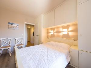 um quarto com uma grande cama branca e uma cadeira em Appartement 1 bedroom at Stella 0602 on floor 6 em Middelkerke