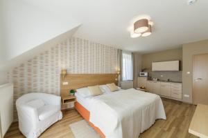 1 dormitorio con 1 cama blanca grande y 1 silla blanca en Penzion U Zemanů Nové Hrady, en Nové Hrady