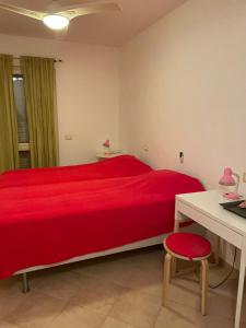 Schlafzimmer mit einem roten Bett, einem Tisch und einem Stuhl in der Unterkunft Casa Lhana in Santa Maria