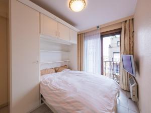 een kleine slaapkamer met een bed en een televisie bij Appartment 2 bedrooms with garage at Marianne I 0501 on floor 5 in Middelkerke