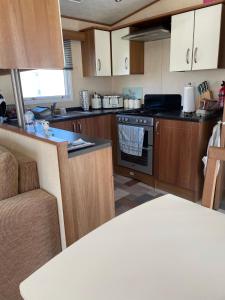 a kitchen with wooden cabinets and a stove top oven at Tags caravan park in Skegness