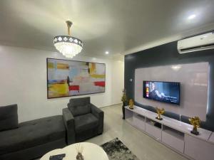 ein Wohnzimmer mit einem Sofa und einem TV in der Unterkunft Keduu beautiful luxury apartment lekki in Lagos