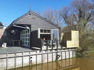 een zwart huis met een terras op een lichaam van water bij B&B De Verre Kijker in Barsingerhorn