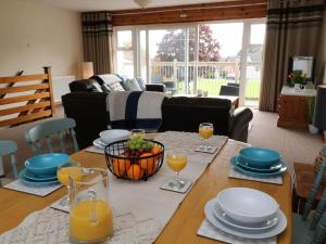 a living room with a table with plates and glasses of orange juice at Cheerful spacious 2 bedroom holiday home St Anns 12 in Gunnislake