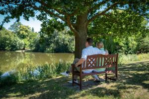 a man and a child sitting on a bench under a tree at Gutshaus Groß Helle in Mölln