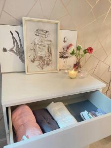 a white shelf with some towels and pictures on it at Daisy Blossom Studio in Bromley