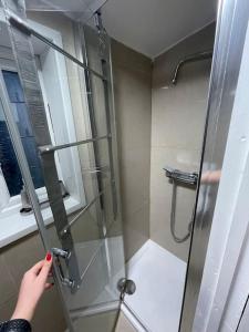 una persona sosteniendo una puerta de ducha de cristal en un baño en Daisy Blossom Studio, en Bromley