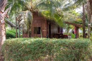 uma casa de madeira com palmeiras em frente em Thai Heritage Koh Mak em Ko Mak
