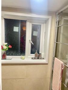 una ventana en un baño con un jarrón de flores en Daisy Blossom Studio, en Bromley