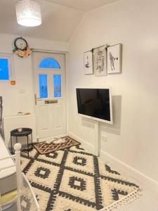 a living room with a flat screen tv on a wall at Daisy Blossom Studio in Bromley