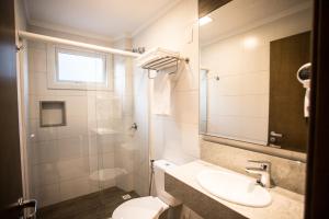 W łazience znajduje się umywalka, toaleta i lustro. w obiekcie Hotel Fioreze Centro w mieście Gramado