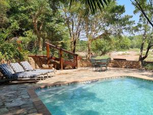 una piscina con patio, mesa y sillas en Paradise River Lodge, en Hoedspruit