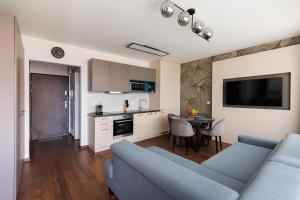 ein Wohnzimmer mit einem blauen Sofa und einer Küche in der Unterkunft Villa Bauhaus Wellness Apartman 102 in Siófok