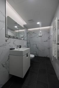 ein weißes Badezimmer mit einem Waschbecken und einem Spiegel in der Unterkunft Villa Bauhaus Wellness Apartman 102 in Siófok