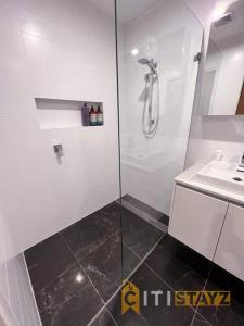 ein weißes Bad mit einer Dusche und einem Waschbecken in der Unterkunft Black & White Delight - 2bd 2bth Apt - Braddon in Canberra