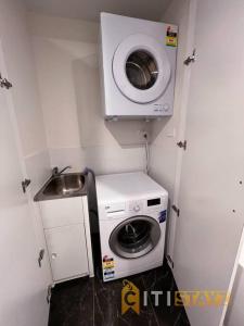 eine kleine Küche mit einer Waschmaschine und einem Waschbecken in der Unterkunft Black & White Delight - 2bd 2bth Apt - Braddon in Canberra