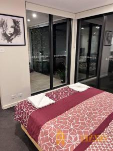 ein Schlafzimmer mit einem Bett in einem Zimmer mit Fenstern in der Unterkunft Black & White Delight - 2bd 2bth Apt - Braddon in Canberra