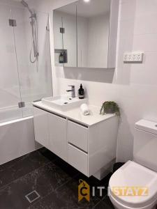 ein weißes Bad mit einem Waschbecken und einem WC in der Unterkunft Black & White Delight - 2bd 2bth Apt - Braddon in Canberra