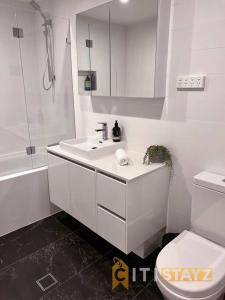 a white bathroom with a sink and a toilet at Black & White Delight - 2bd 2bth Apt - Braddon in Canberra