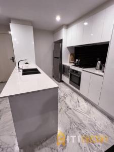 eine weiße Küche mit einer Spüle und einem Kühlschrank in der Unterkunft Black & White Delight - 2bd 2bth Apt - Braddon in Canberra