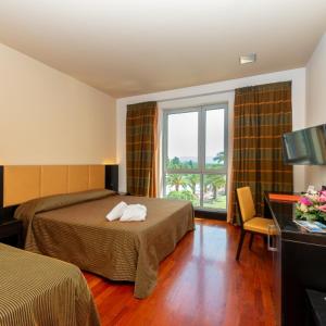 a hotel room with two beds and a window at Victoria Terme Hotel in Tivoli Terme