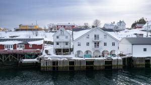 una città con tetti ricoperti di neve e case vicino all'acqua di The Tide - Rorbuer a Sørvågen