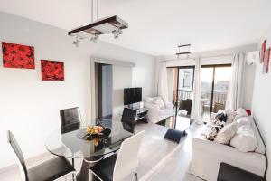 a white living room with a glass table and white chairs at Alexis Apartments - Lovely 2-bedroom with swimming pool in Paphos City