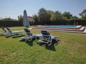 een groep ligstoelen en een parasol naast een zwembad bij la Casita in Carmona