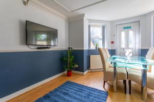 a dining room with a glass table and a tv at West Hill Stays Chapel Alleton LS7 - 3 bed Sleeps 5 - close to City Center - free parking - contractor welcome in Moortown