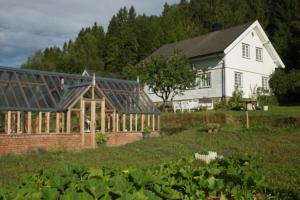 a greenhouse in front of a white house at Idyllic small farm appartment in Tønsberg
