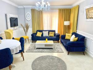 ein blaues Wohnzimmer mit blauen Sofas und gelben Kissen in der Unterkunft Cozy Apartment (JANNA) in Madinat as-Sadis min Uktubar