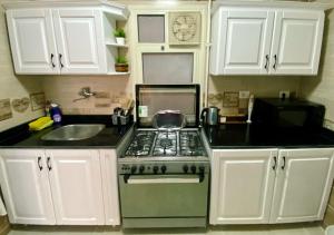 una cucina con piano cottura, lavello e armadietti bianchi di Cozy Apartment (JANNA) a Città del 6 ottobre