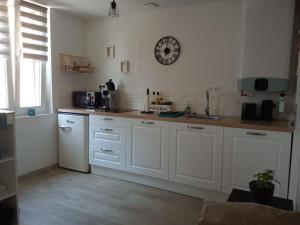 kuchnia z białymi szafkami i zegarem na ścianie w obiekcie Bienvenue chez vous w mieście Cormeilles +6 zdjęć