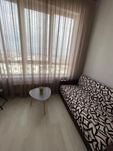 een slaapkamer met een bed en een tafel voor een raam bij Comfortable apartment with a panoramic view in Chişinău