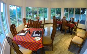 a dining room with tables and chairs and windows at Winter Villa in Kandy