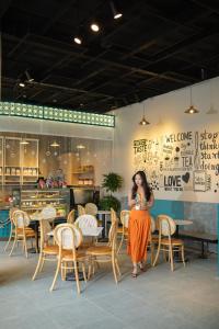 Una mujer con un vestido naranja parada frente a un restaurante en Odin Hotel Quy Nhon en Quy Nhon