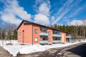an orange apartment building with snow on the ground at Hiisi Homes Kirkkonummi Laajakallio in Kirkkonummi