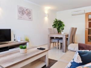 ein Wohnzimmer mit Fernseher und Tisch in der Unterkunft SÍTIO DO RAPOSO - Carvoeiro - WiFi, AC, Beach & Center 200m in Carvoeiro