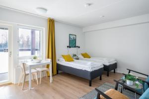 a room with two beds and a table at Hiisi Homes Kirkkonummi Laajakallio in Kirkkonummi