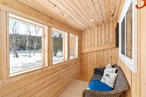 een blokhut met een bank in een kamer met ramen bij Cozy Cabin for Intimate Wilderness Escape in Bathurst