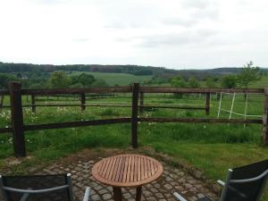 a wooden fence with a table and chairs in front of a field at "Die Jockeysuite" auf unserem Reiterhof in Birkenbeul