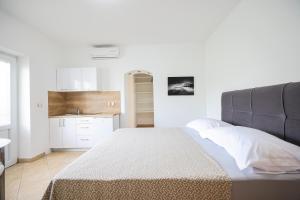 a white bedroom with a bed and a kitchen at Apartments Marina in Petrcane